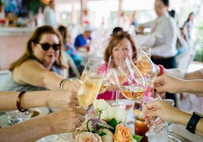Group of people toasting with champagne glasses at a festive table with flowers.