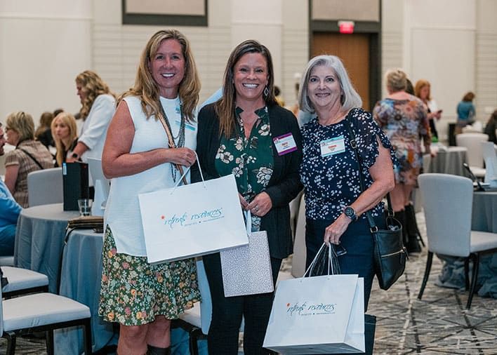 Three happy women holding goodie bags during Retreats Resources’ Classic Southeast Roadshow.